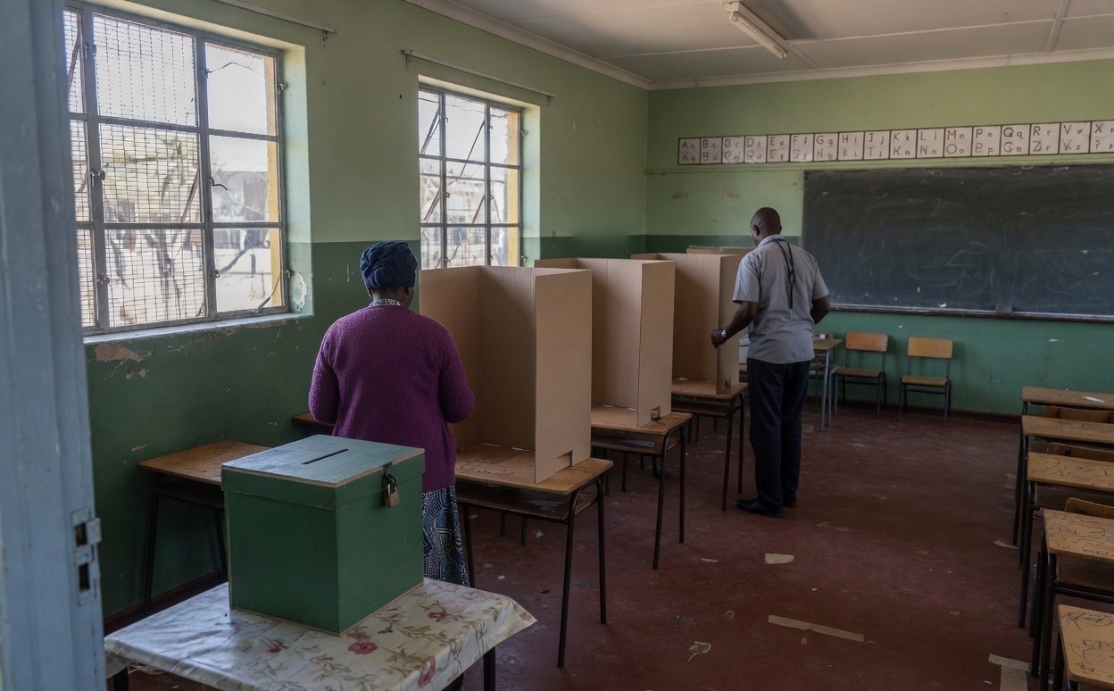 Illustrative scene of a classroom arranged as a polling station with cardboard screens and a ballot box
